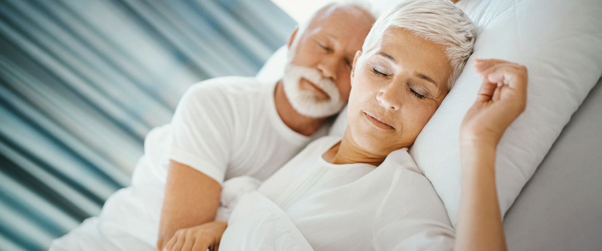 Man and woman sleeping soundly in bed with white covers